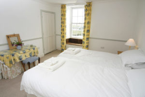 A light and spacious bedroom with twin beds, dressing table and a beautiful bay window seat