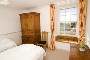A light and spacious bedroom with twin beds, and a beautiful bay window seat
