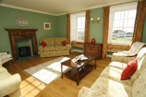 A light and spacious drawing room with beautiful bay windows, wooden floors and fireplace