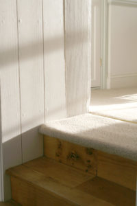 Close up of the cream carpeted top step of a wooden staircase