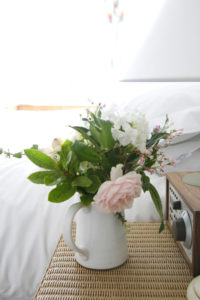 Fresh Flowers in a vase on a bedside table in a bright in bedroom