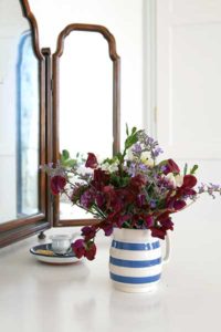 Fresh flowers in a blue and white striped vase in front of an ornate mirror