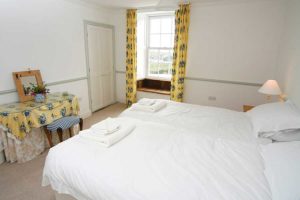 A light and spacious bedroom with twin beds, a dressing table and a beautiful bay window seat