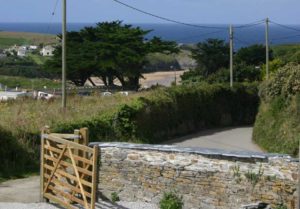 A country lane leading to a property with a wooden gate and stone walls