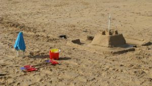A sandcastle, bucket and spades on a sandy beach