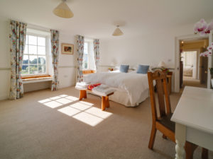 A light and spacious bedroom with a large bed, a dressing table and beautiful bay window seats