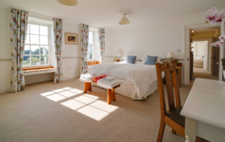 A light and spacious bedroom with a large bed, a dressing table and beautiful bay window seats