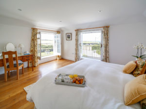 A light and spacious bedroom with a large bed, dressing table and wooden floors