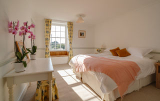A light and spacious bedroom with twin beds , a dressing table and a beautiful bay window seat